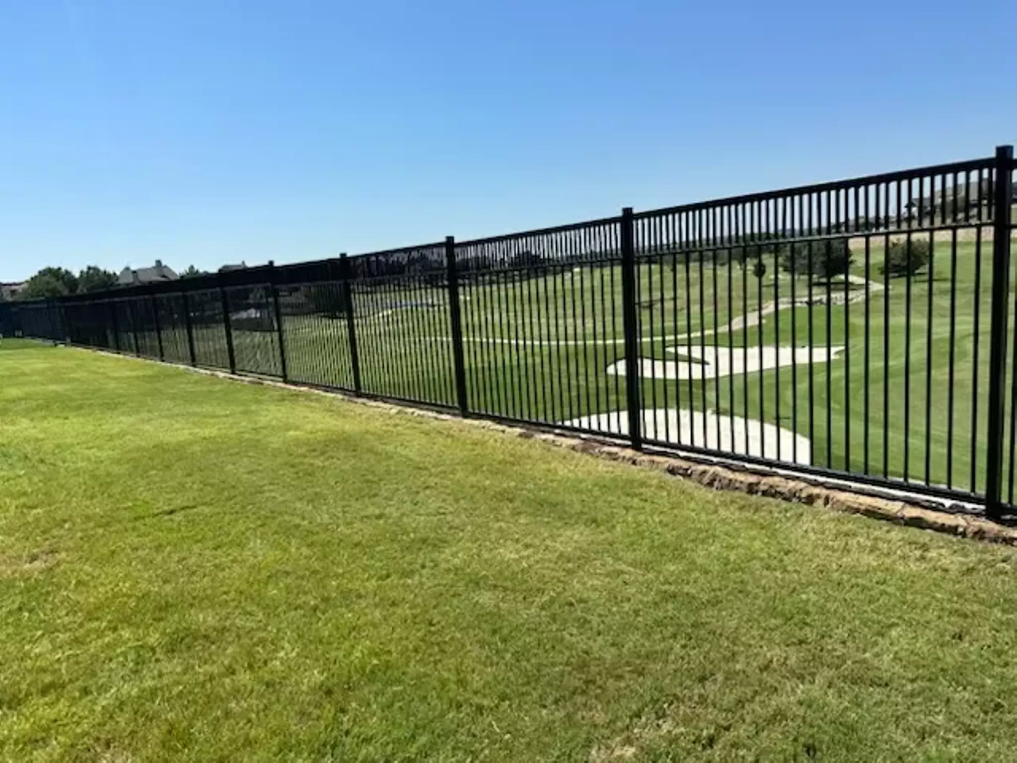 Black wrought iron fence on a golf course