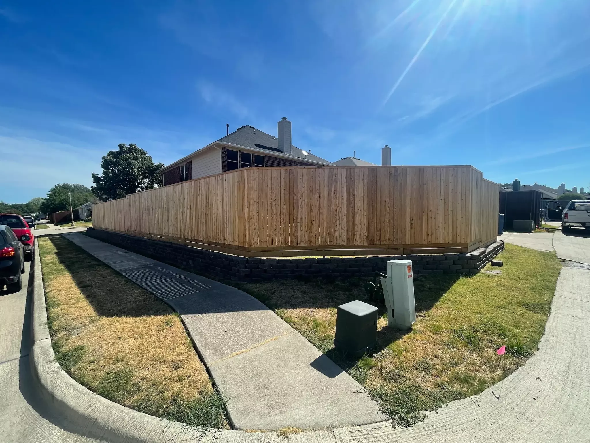 Unstained wooden fence in a residential backyard from the sidewalk