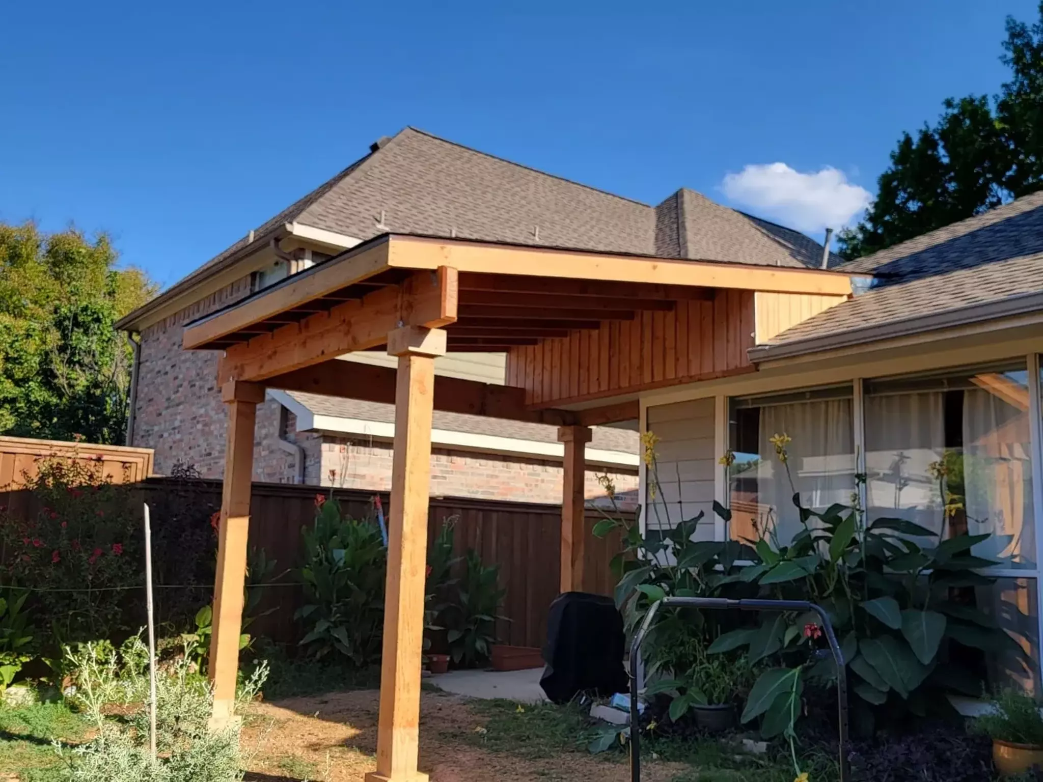 Bright acacia-colored patio cover attached to the back of a brick house