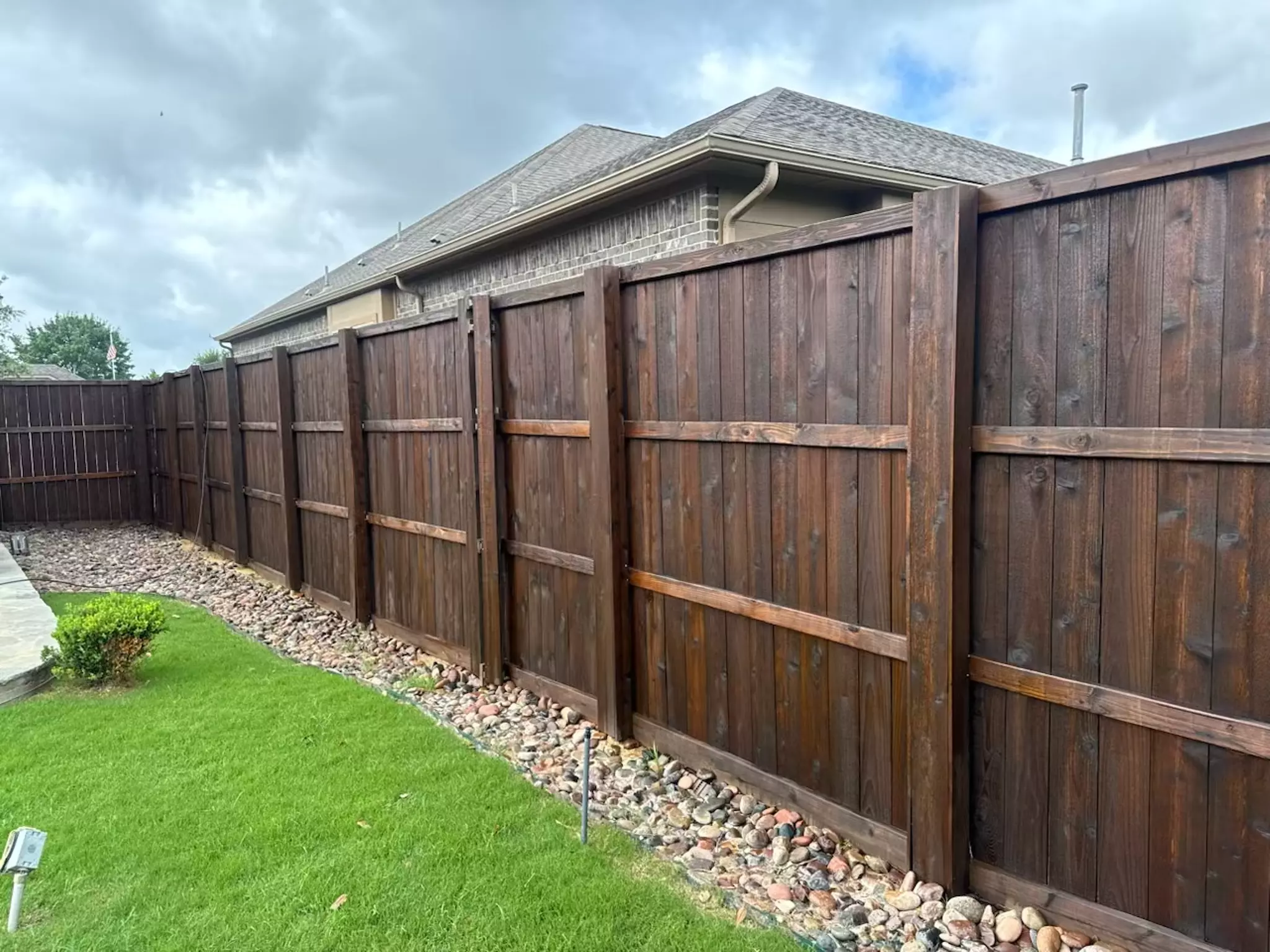 Dark brown stained wooden fence in a residential backyard